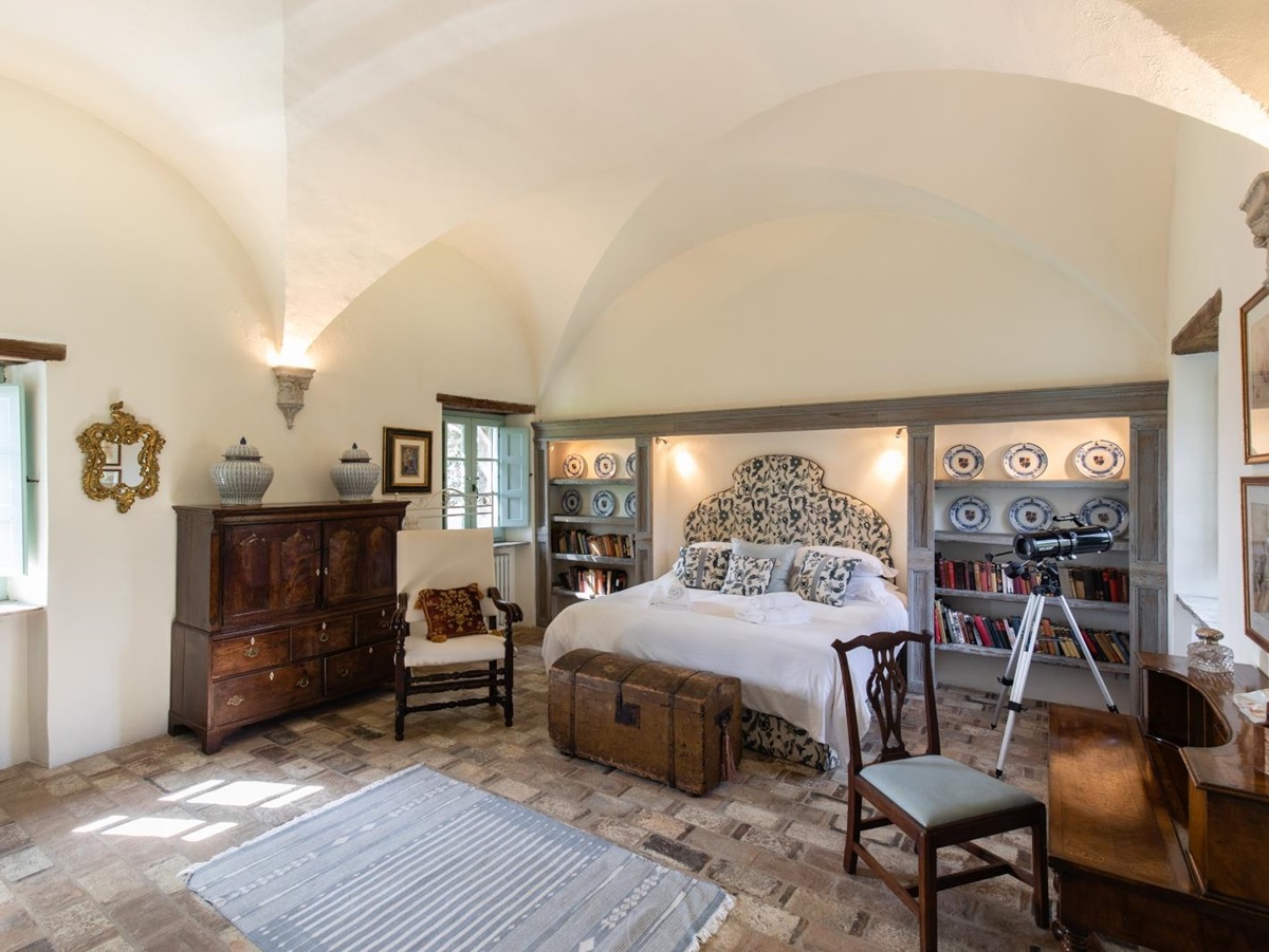Bedroom with double bed, chest, chairs, desk, books, plates, telescope and cabinet at Tenuta Cantata in Tuscany, Italy