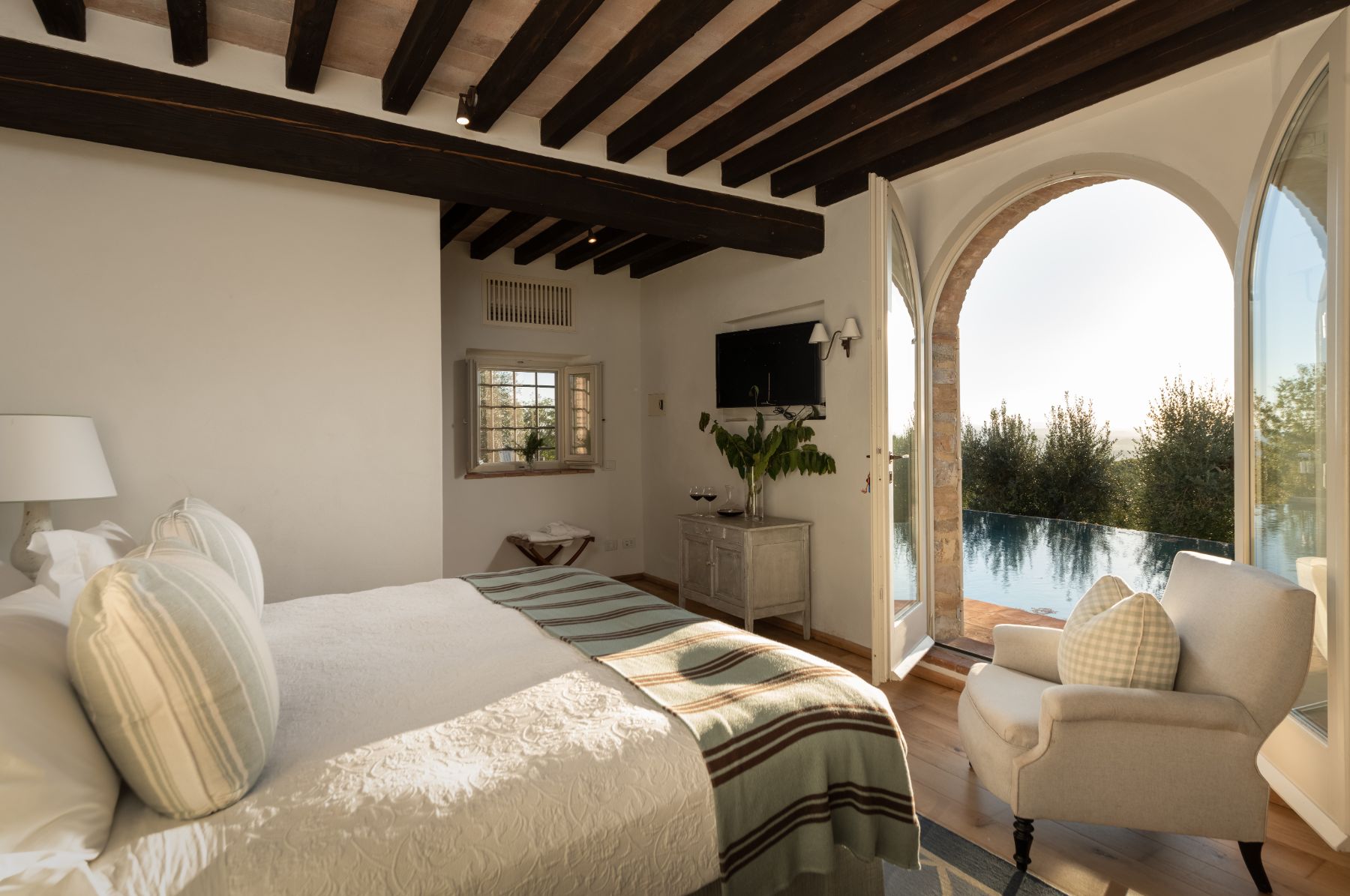 Bedroom with large double bed and open doors overlooking the pool at Tramonti in Tuscany