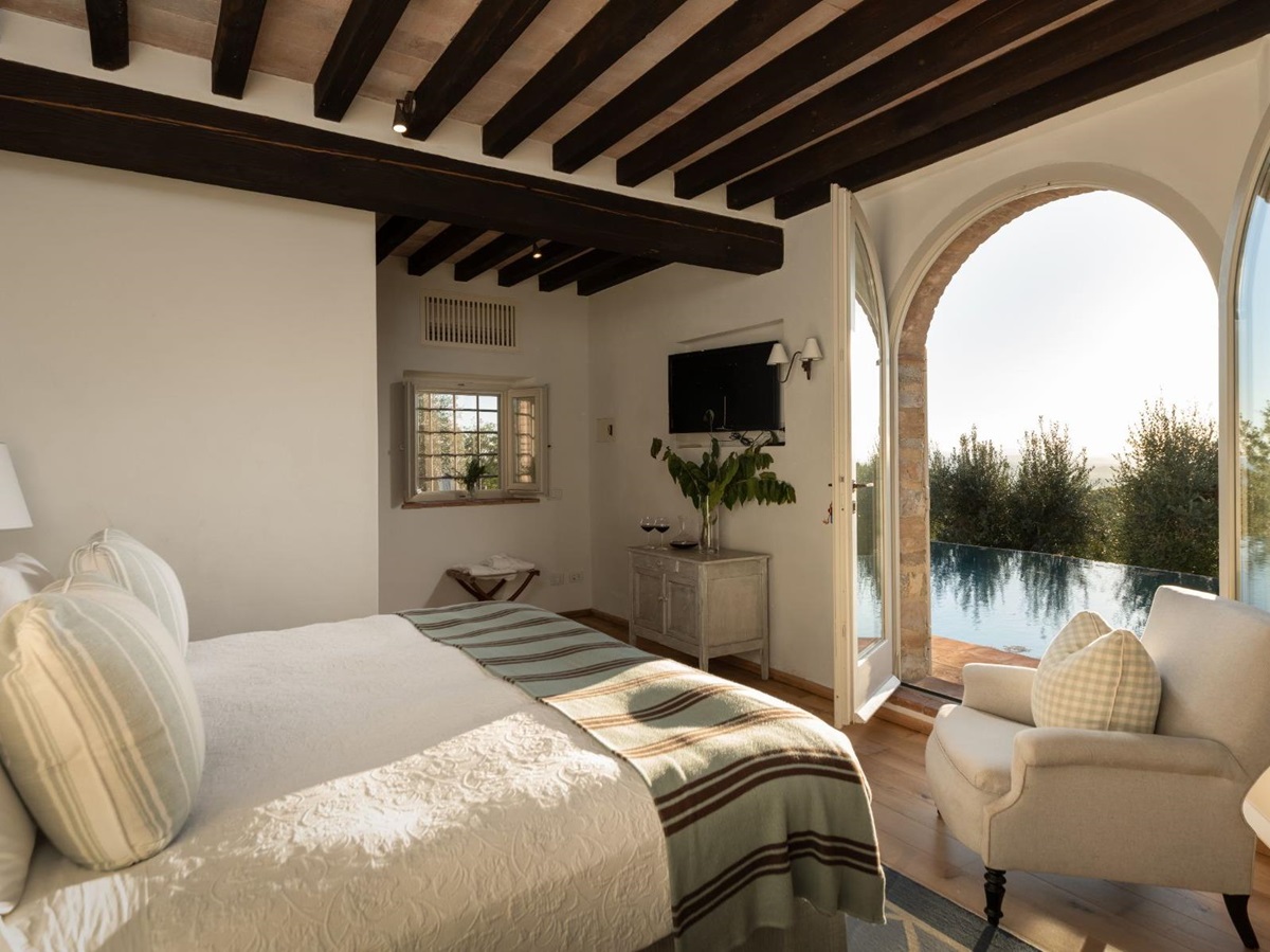 Bedroom with large double bed and open doors overlooking the pool at Tramonti in Tuscany