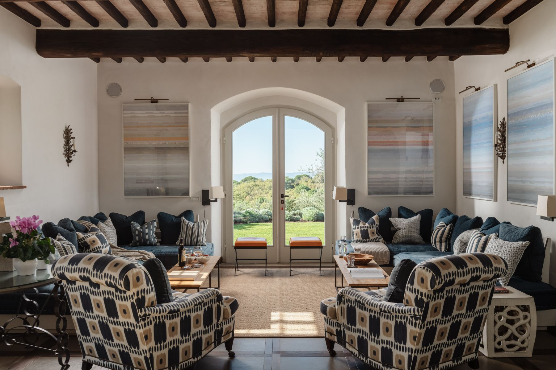 Indoor lounge room with sofas and armchairs and large french windows at Tramonti in Tuscany