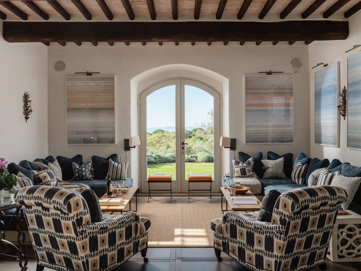 Indoor lounge room with sofas and armchairs and large french windows at Tramonti in Tuscany