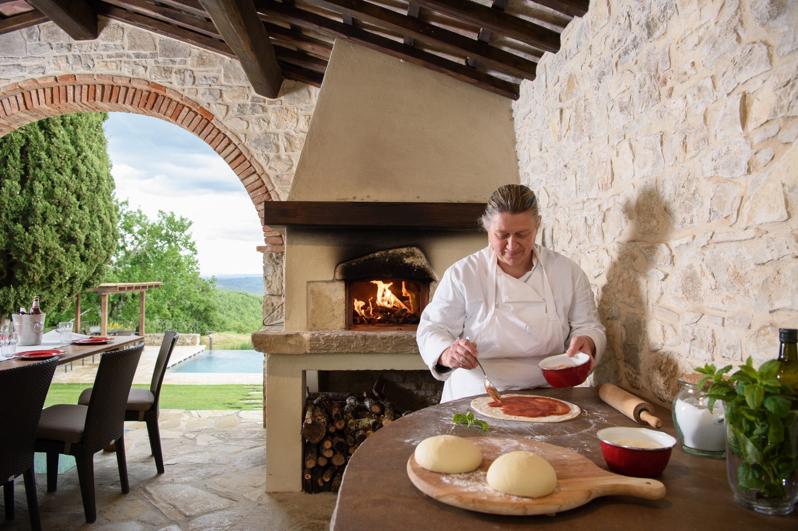 Pizza making by pool with wood fired pizza oven and chef at Tramonti in Tuscany, Italy