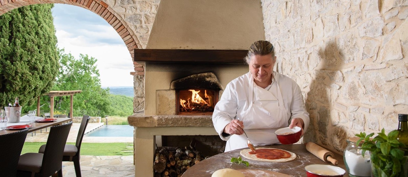 Pizza making by pool with wood fired pizza oven and chef at Tramonti in Tuscany, Italy
