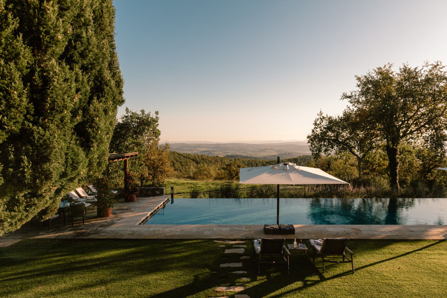 Outdoor pool area with sun loungers and parasols overlooking the Tuscan hills at Tramonti