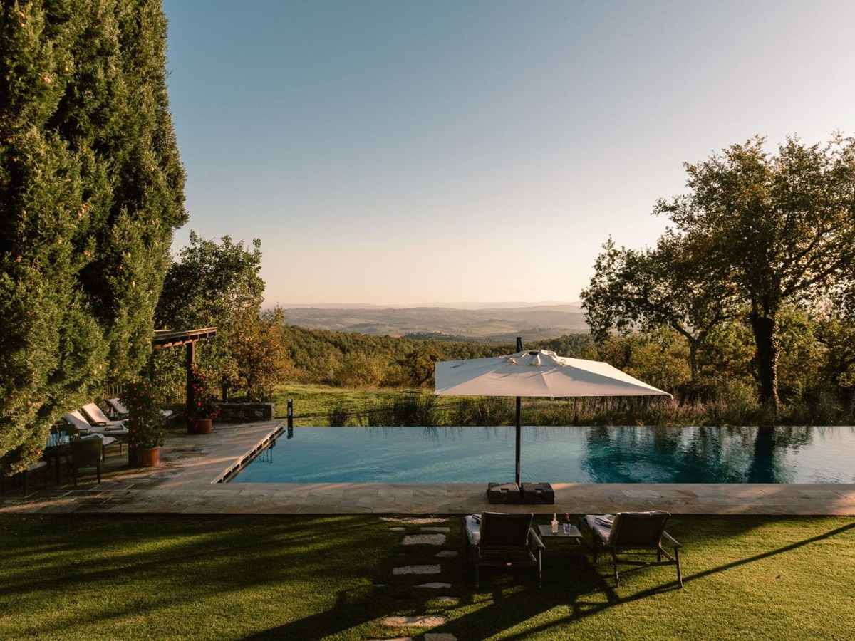 Outdoor pool area with sun loungers and parasols overlooking the Tuscan hills at Tramonti