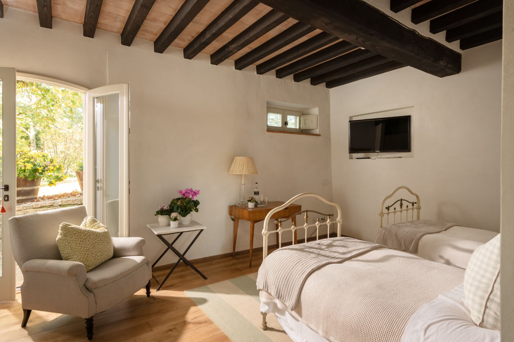 Twin room with an armchair and french windows at Tramonti in Tuscany