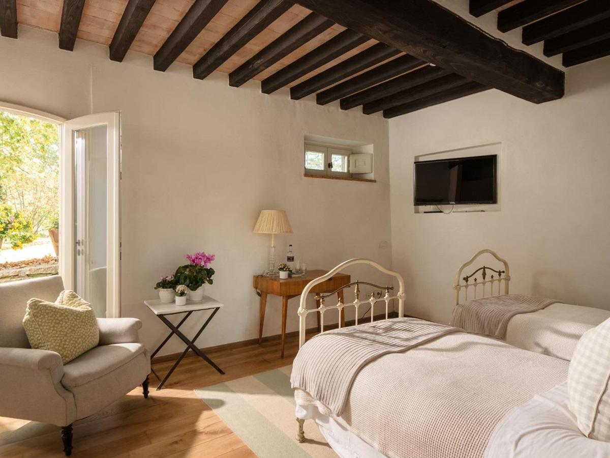 Twin room with an armchair and french windows at Tramonti in Tuscany
