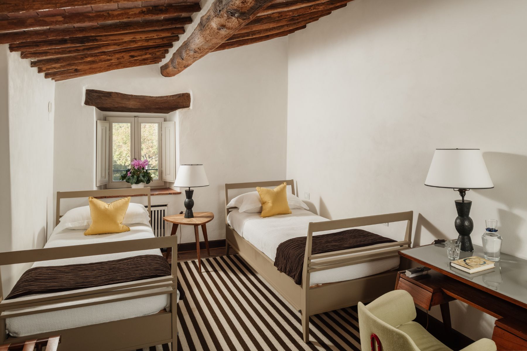 Twin room with striped carped and a desk at Tramonti in Tuscany