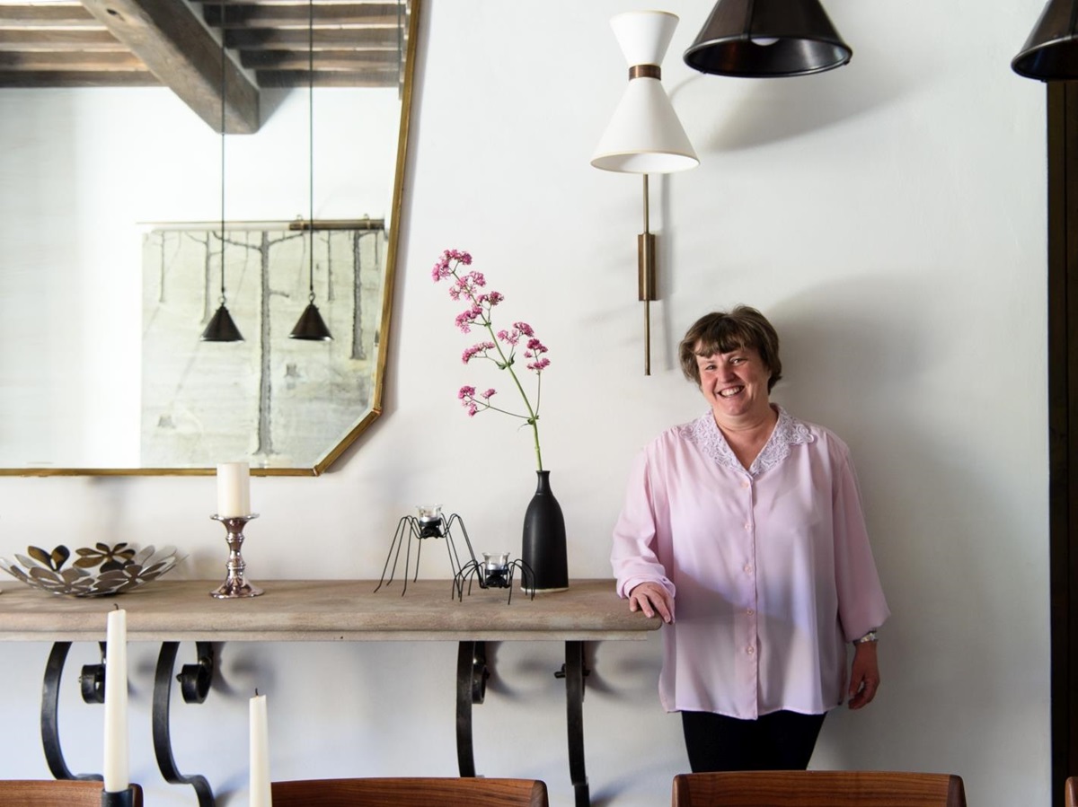 Villa manager in dining room with console table, mirror, candles, flowers and hanging lights at Tramonti in Tuscany, Italy