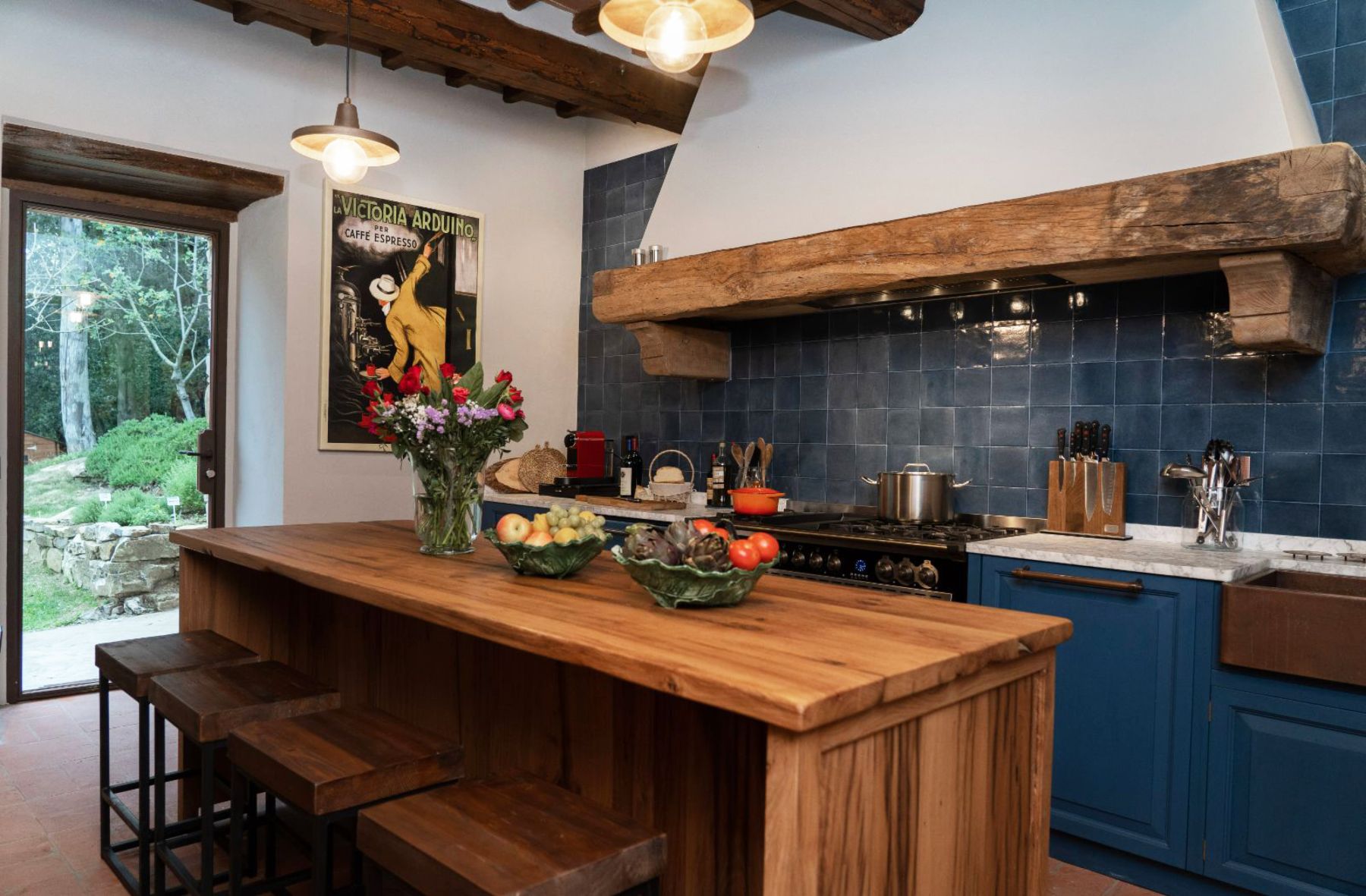 Kitchen with blue tiles and work tops and a wooden island at Villa Ardore in Tuscany