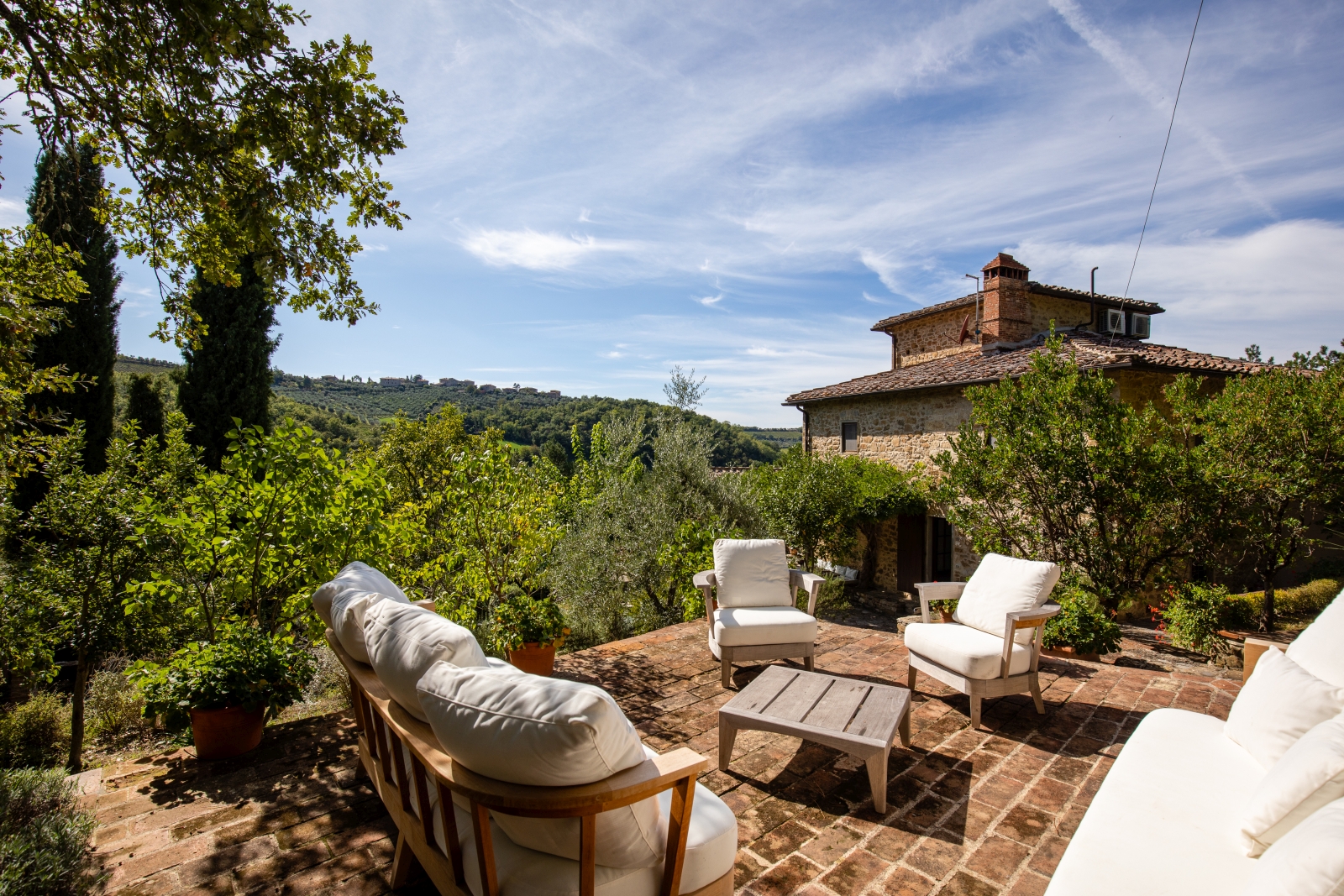 Patio with comfy chairs, coffee table and countryside view at the back of Villa Baciata in Tuscany, Italy
