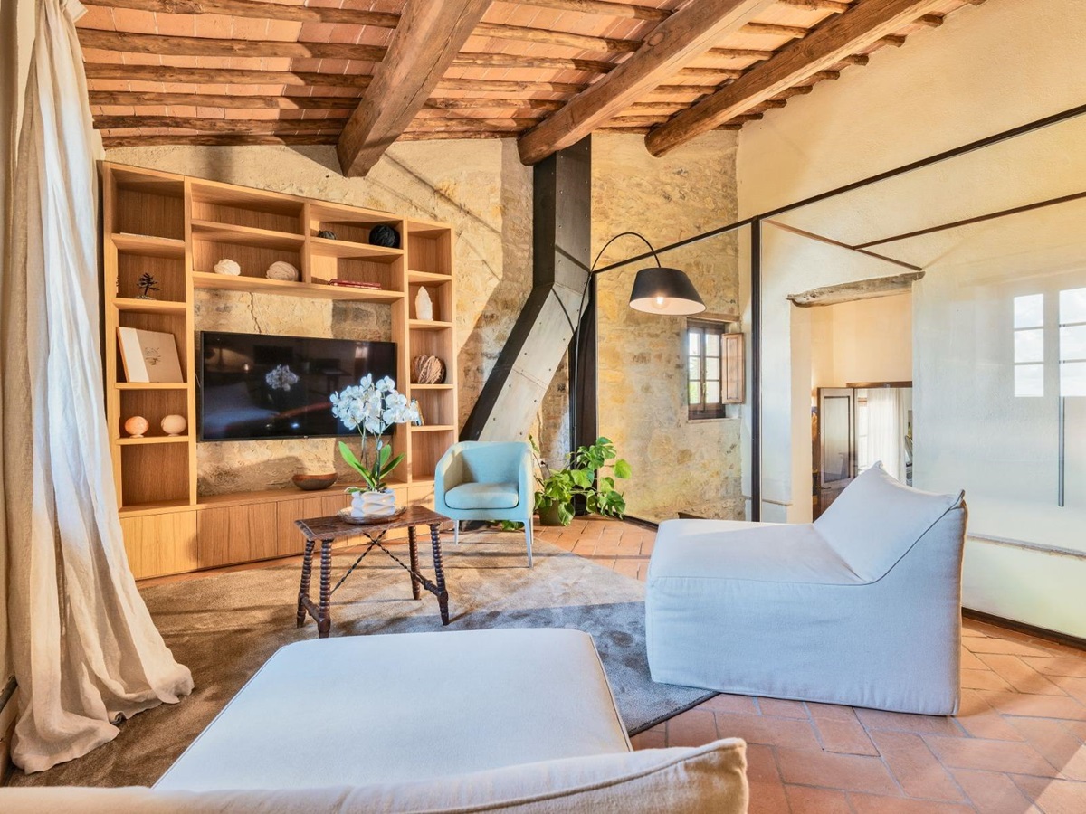 Indoor living area with large wooden shelves and comfy seats with Tv on wall at Villa Cispiano in Tuscany