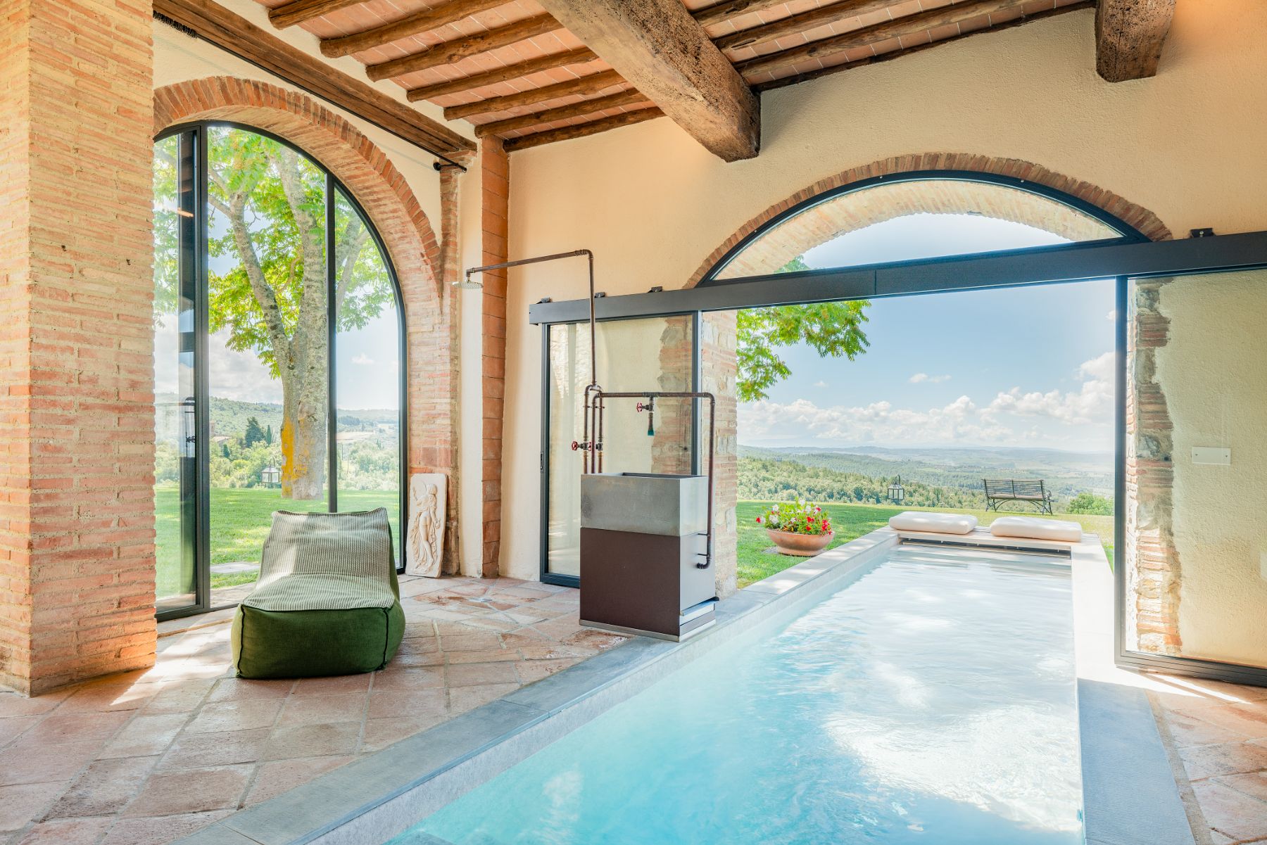 Indoor pool with view of sun loungers and windows with outdoor views at Villa Cispiano in Tuscany