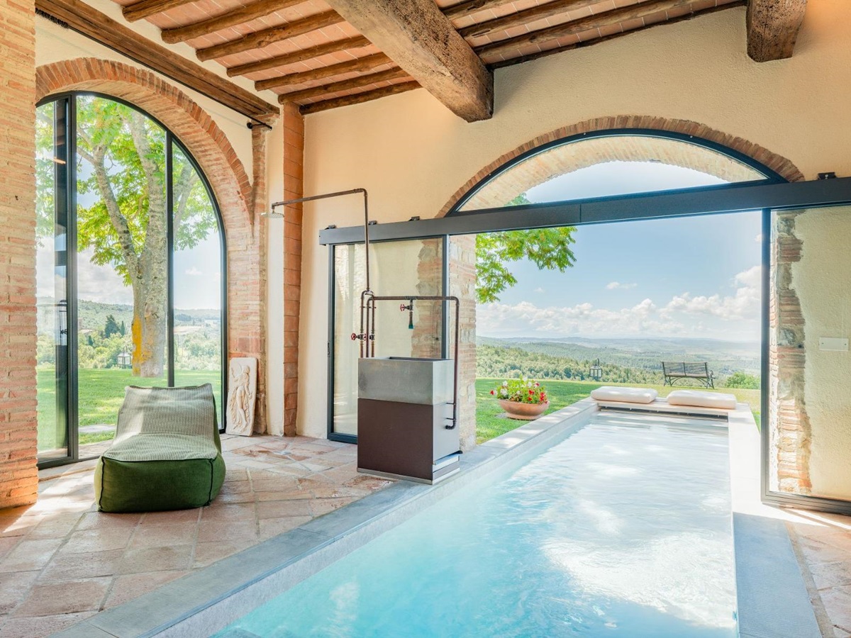 Indoor pool with view of sun loungers and windows with outdoor views at Villa Cispiano in Tuscany