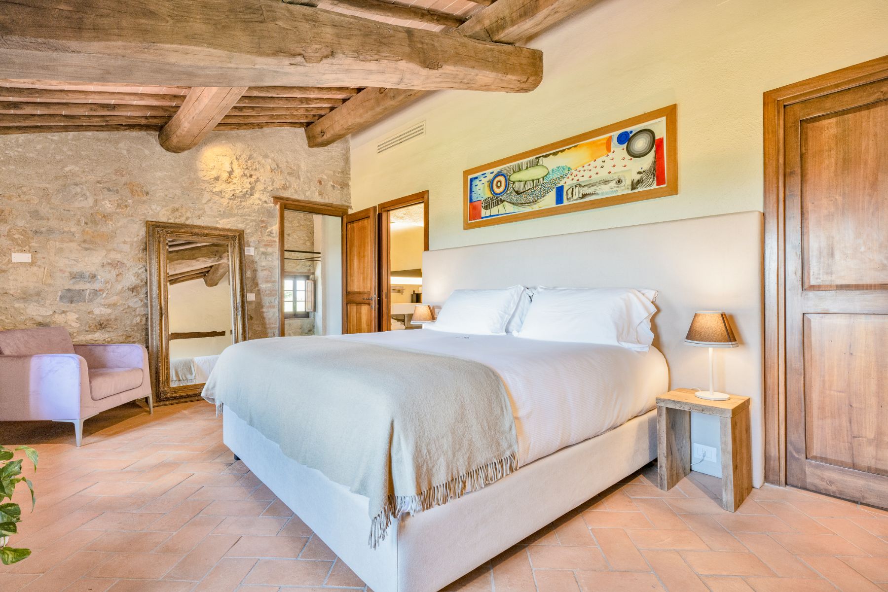 Master bedroom with large bed and painting on wall at Villa Cispiano in Tuscany