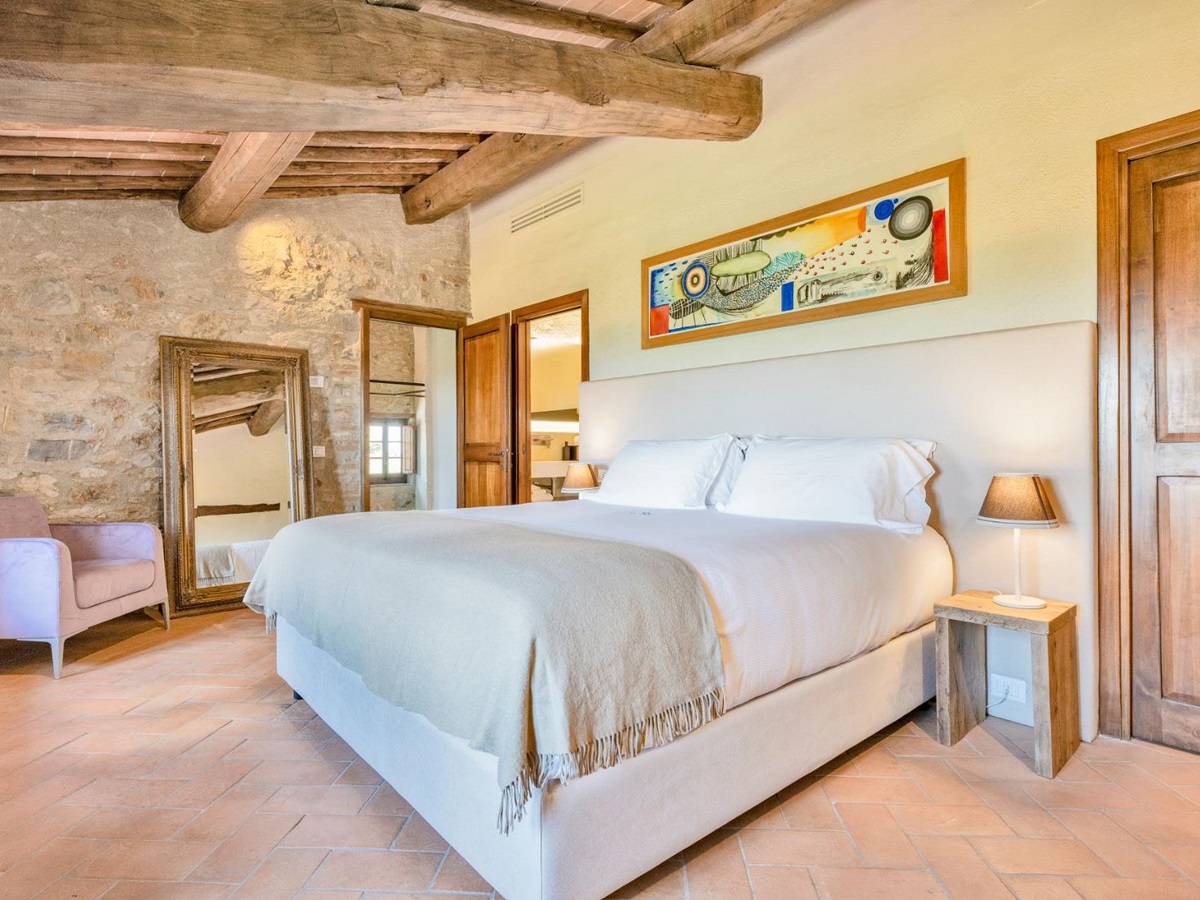 Master bedroom with large bed and painting on wall at Villa Cispiano in Tuscany