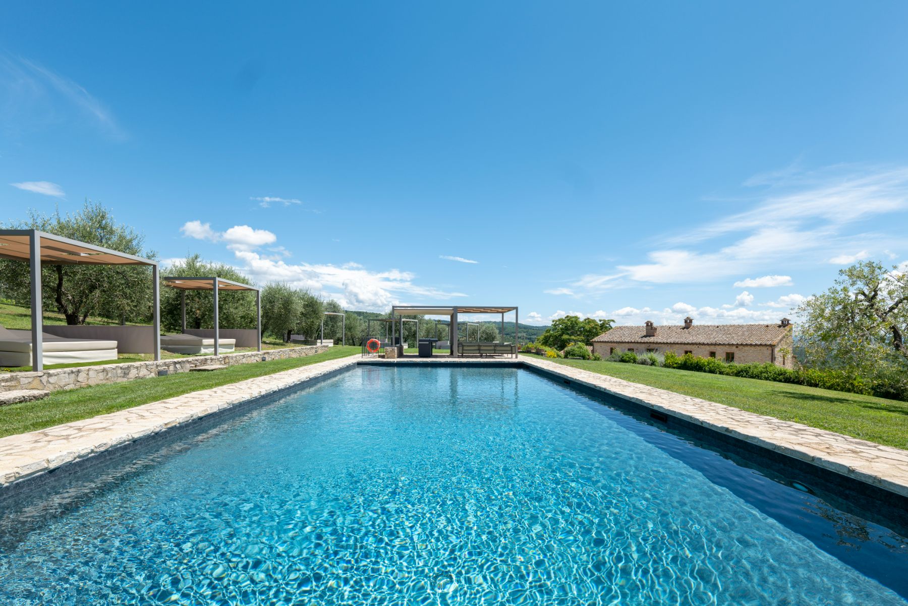 Pool view with sun cabanas on the left side at Villa Cispiano in Tuscany