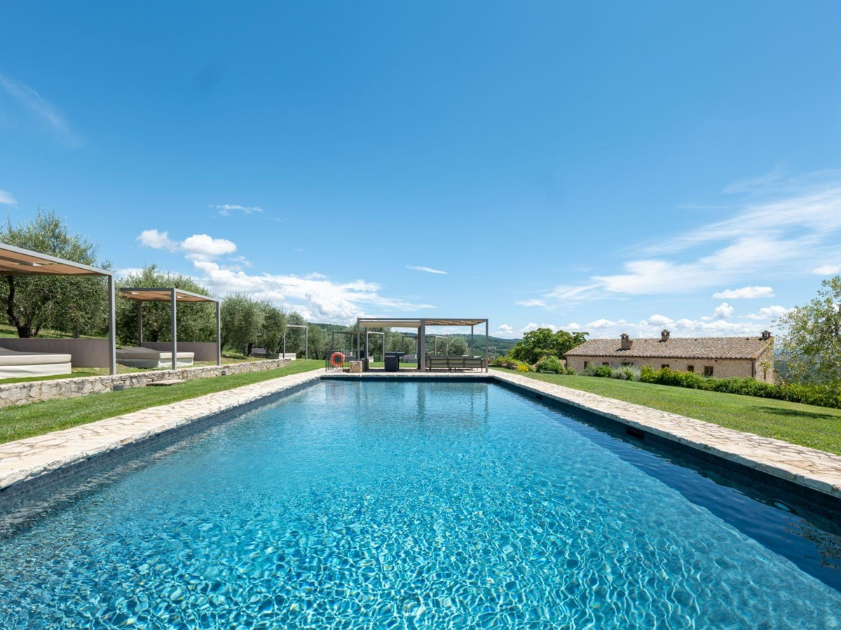Pool view with sun cabanas on the left side at Villa Cispiano in Tuscany