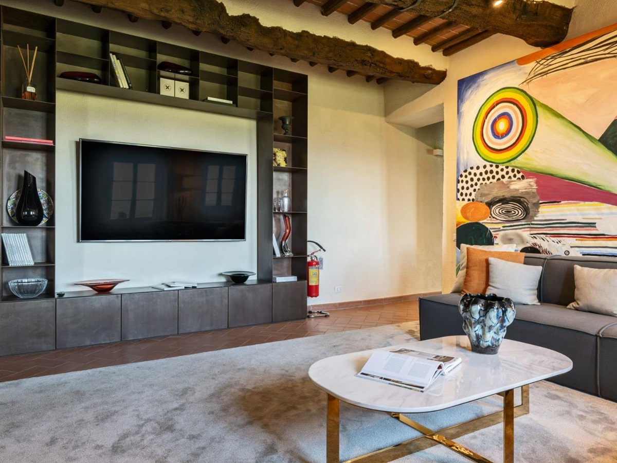 television room with sofas and large television on the wall at Villa Cispiano in Tuscany