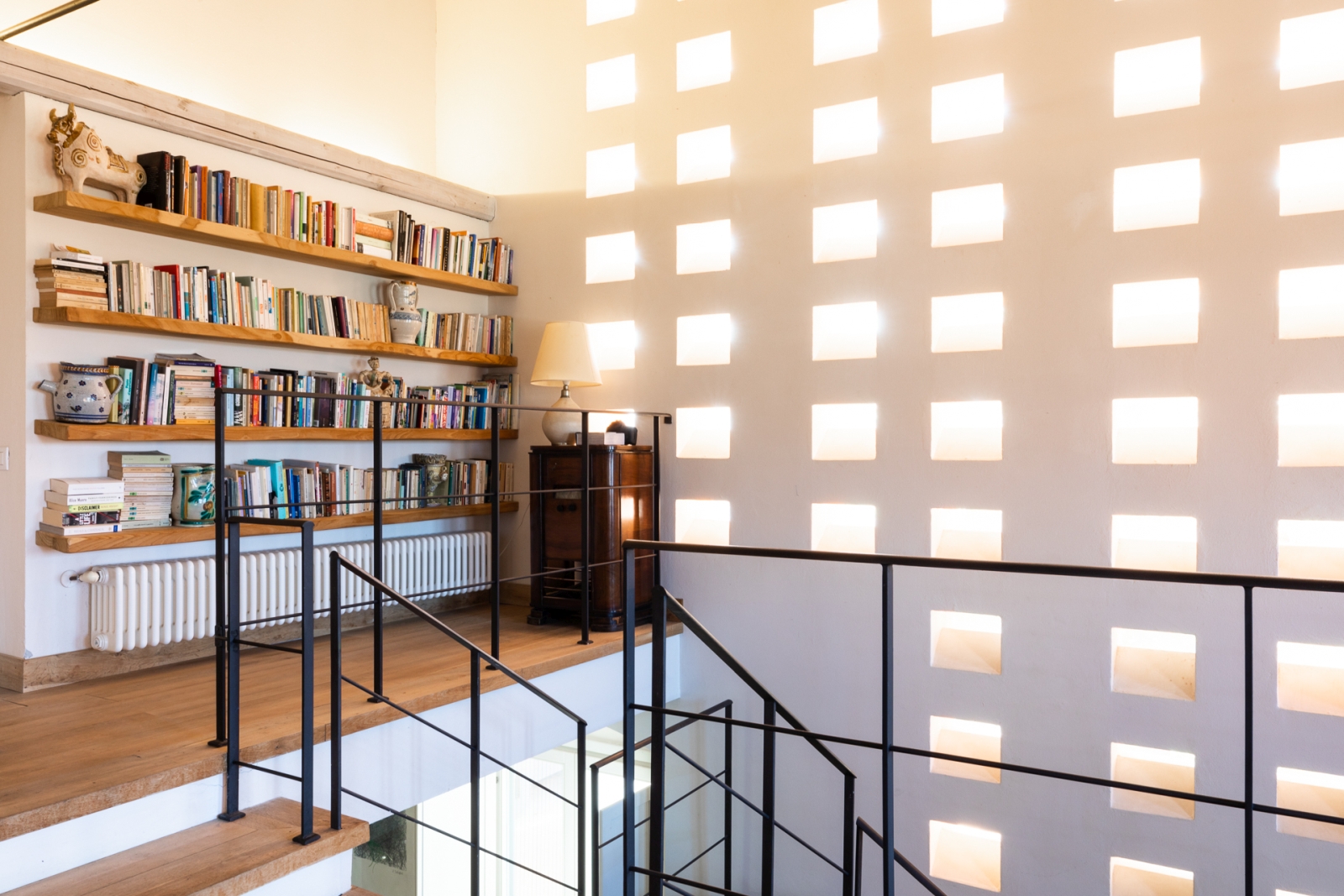 Hallway by stairs with full bookcase at Villa del Gelso, Tuscany