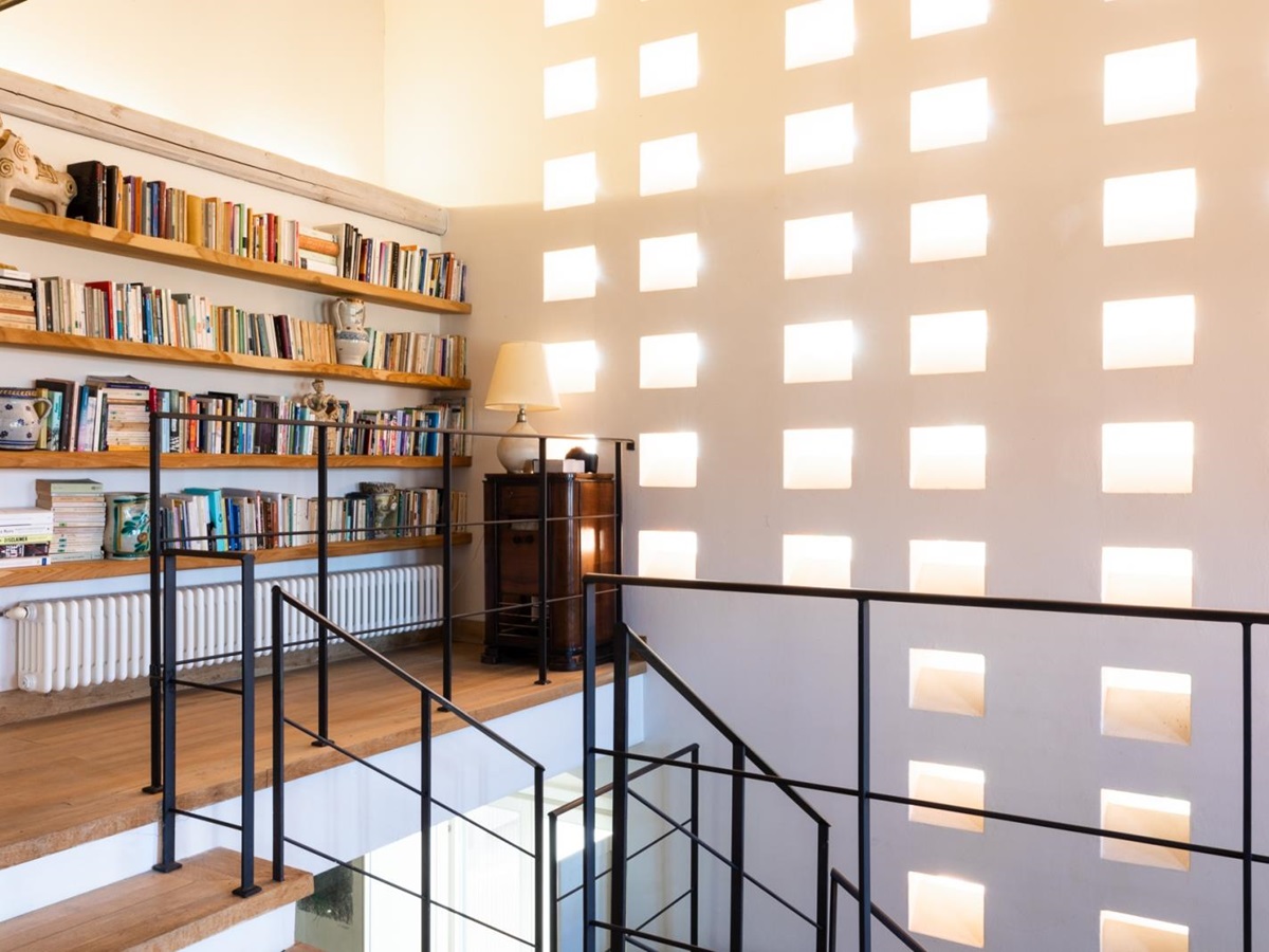 Hallway by stairs with full bookcase at Villa del Gelso, Tuscany