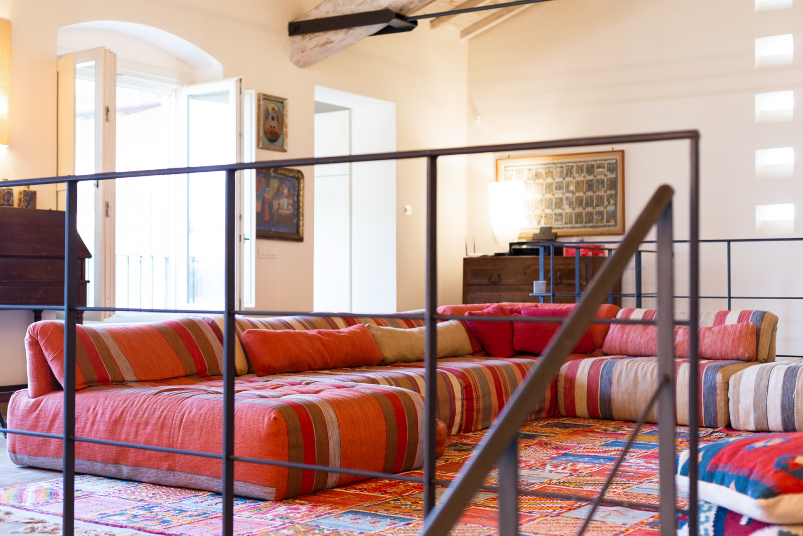 Red corner sofa by the stairs at Villa del Gelso, Tuscany