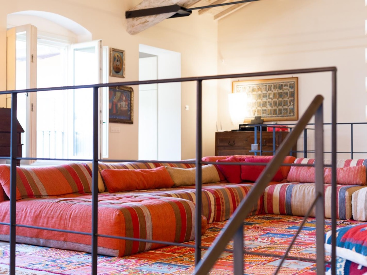 Red corner sofa by the stairs at Villa del Gelso, Tuscany
