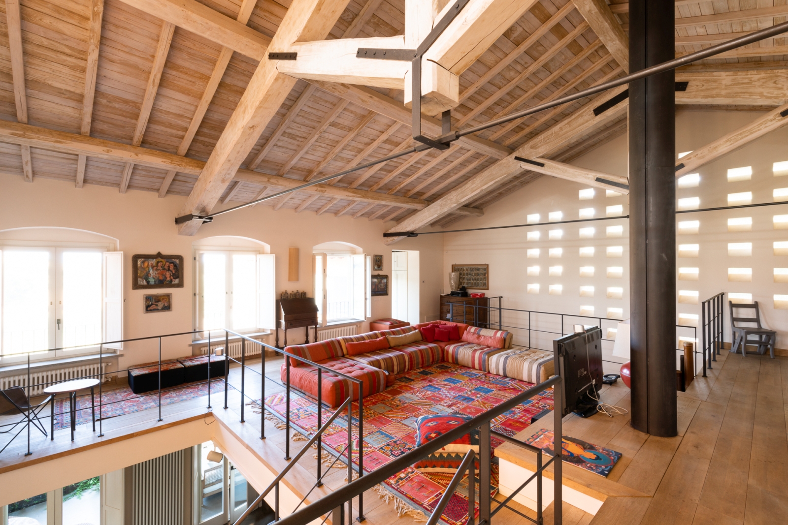 Upstairs living room with red sofa and rug at Villa del Gelso, Tuscany