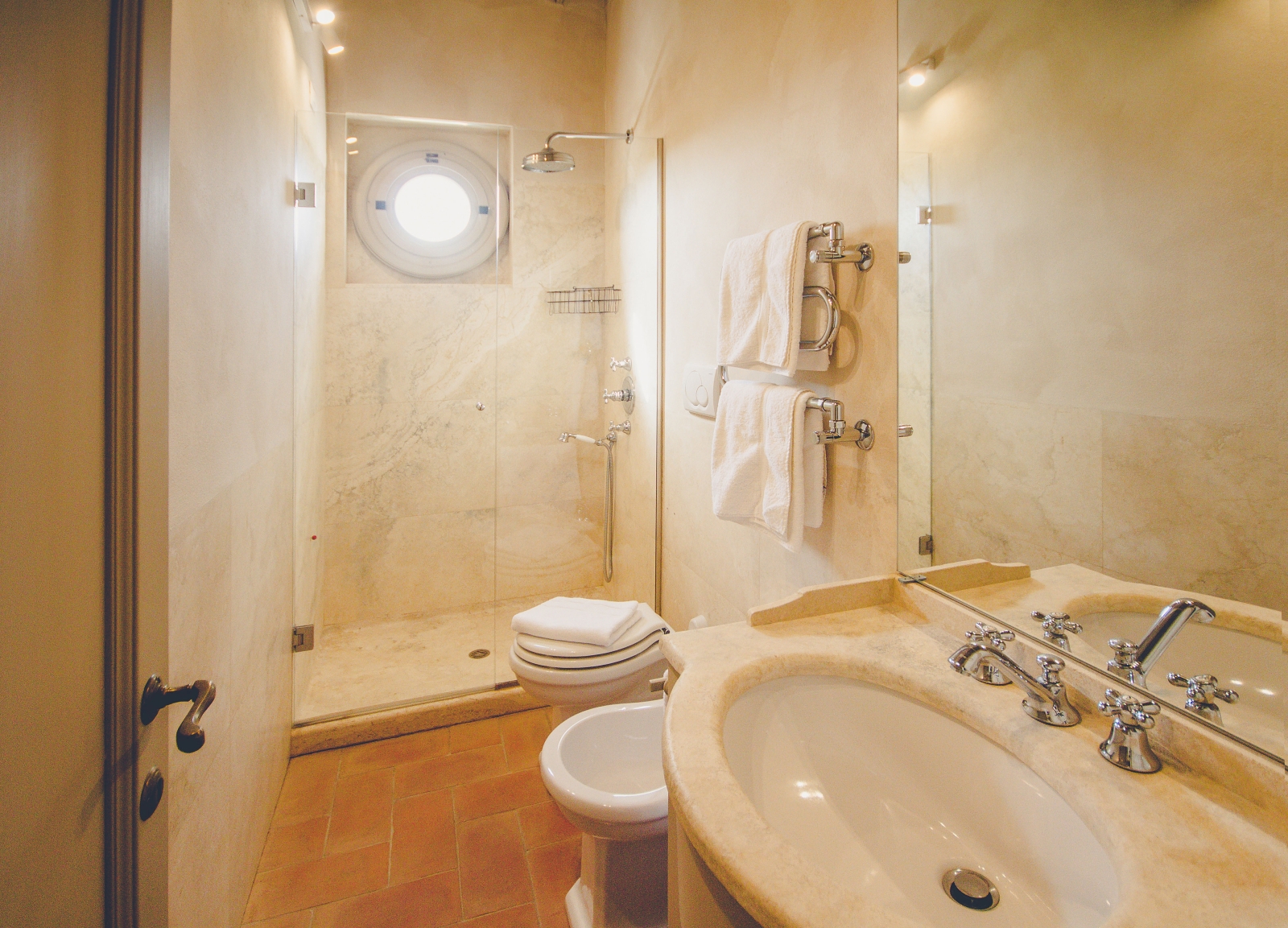 Bathroom with sink, bidet, toilet, shower, small window and towel rails at Villa dell’Angelo in Tuscany, Italy