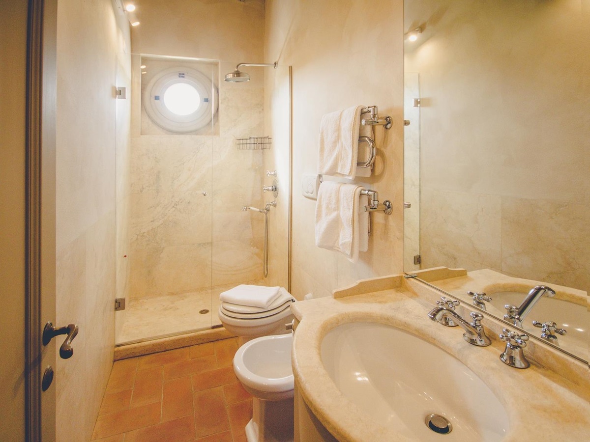 Bathroom with sink, bidet, toilet, shower, small window and towel rails at Villa dell’Angelo in Tuscany, Italy