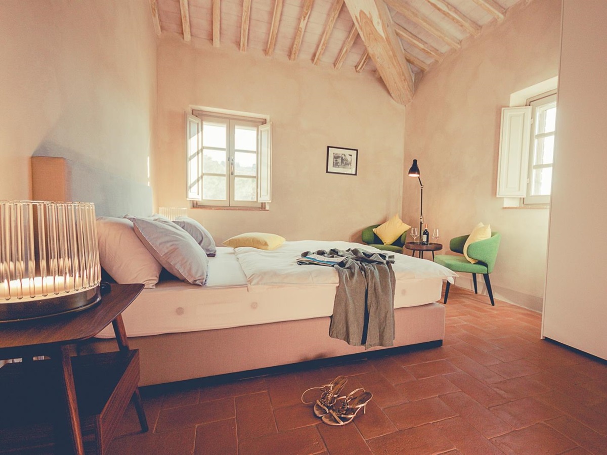 Bedroom with double bed, bedside table, lamp, table, armchair and angle poise lamp at Villa dell’Angelo in Tuscany, Italy