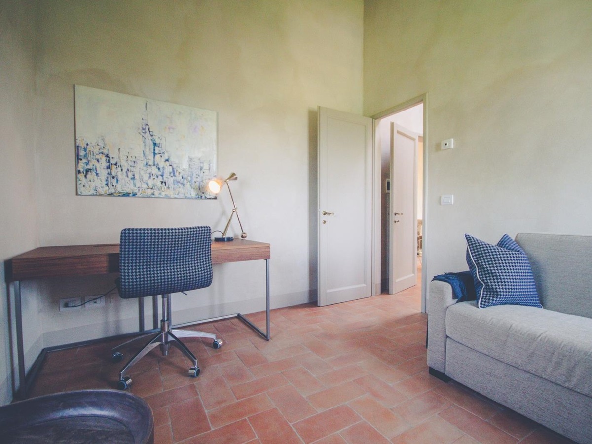 Study with desk, desk chair, lamp, painting and sofa at Villa dell’Angelo in Tuscany, Italy