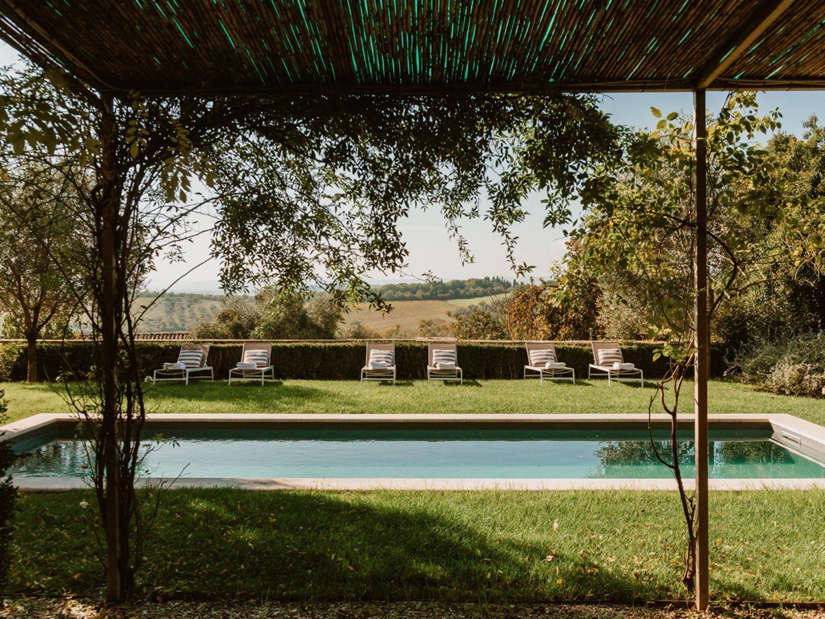Outdoor pool area at Villa delle Vigne in Tuscany surrounded by grass with sunloungers