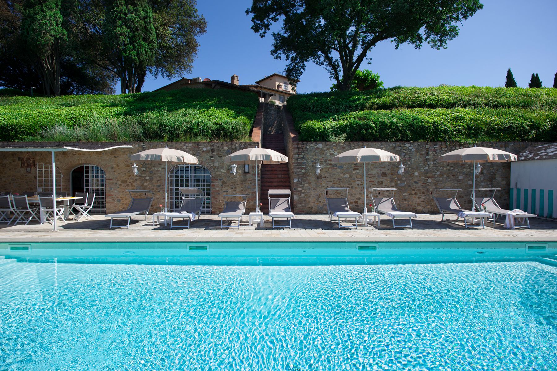 Pool area with view of the outdoor pool and sunbeds at Villa di Tignano in Tuscany