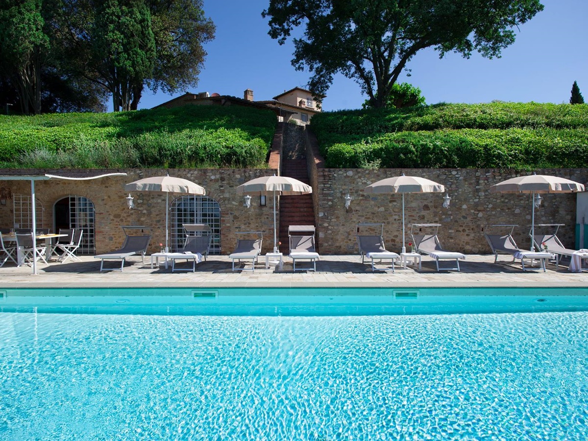 Pool area with view of the outdoor pool and sunbeds at Villa di Tignano in Tuscany