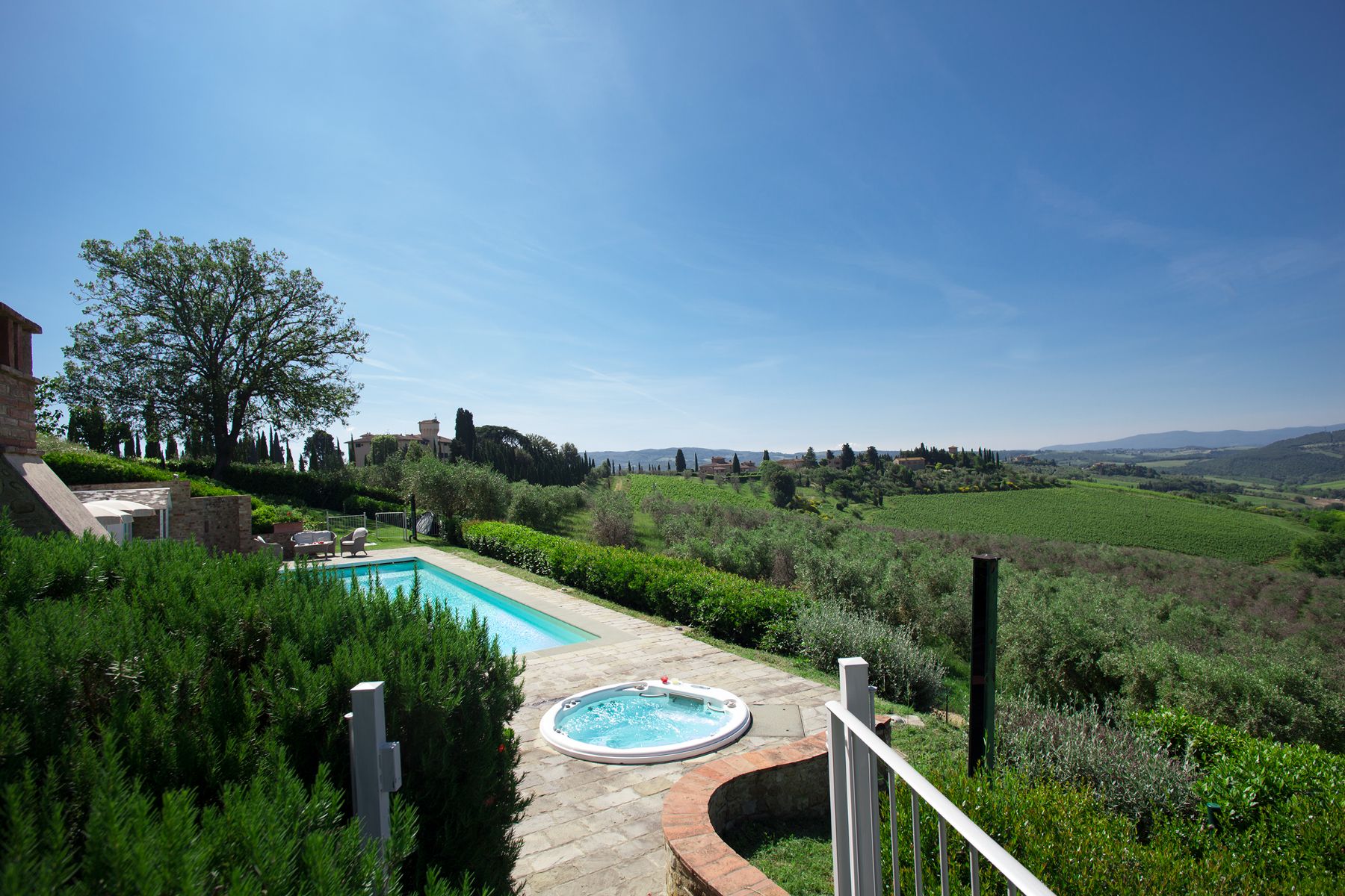 View of the pool area and jacuzzi from the garden with views of hills in front at Villa di Tignano in Tuscany