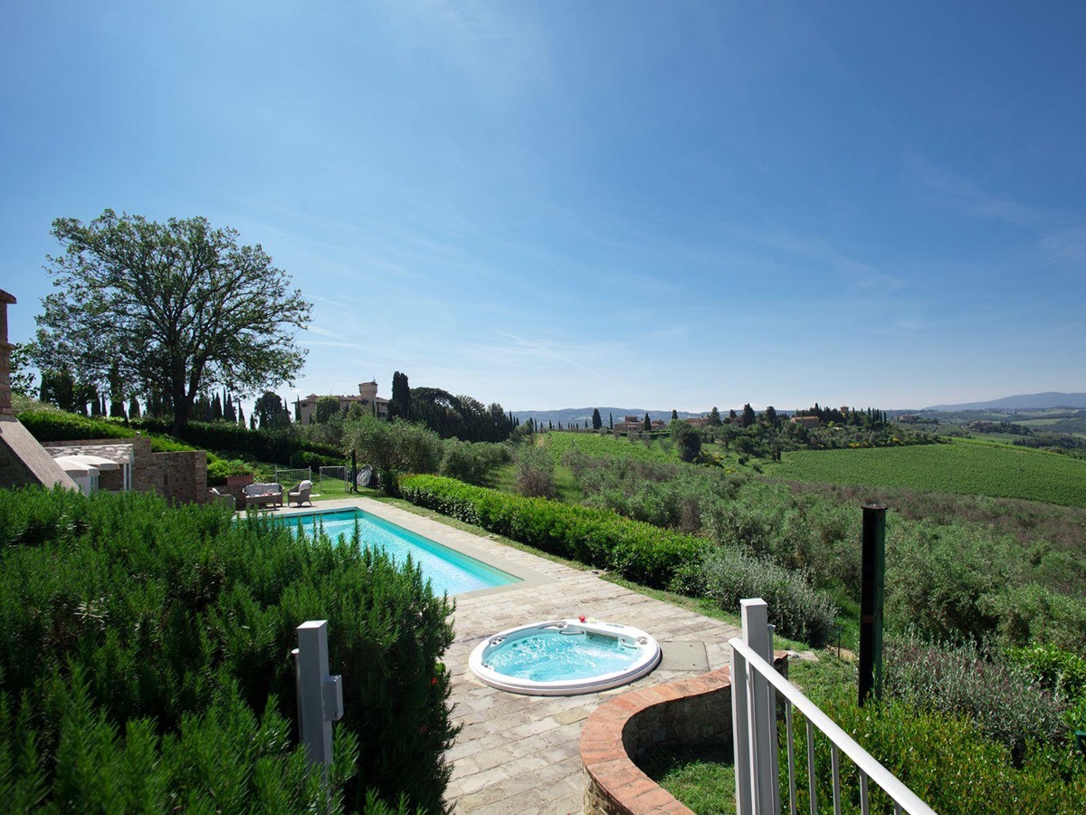 View of the pool area and jacuzzi from the garden with views of hills in front at Villa di Tignano in Tuscany