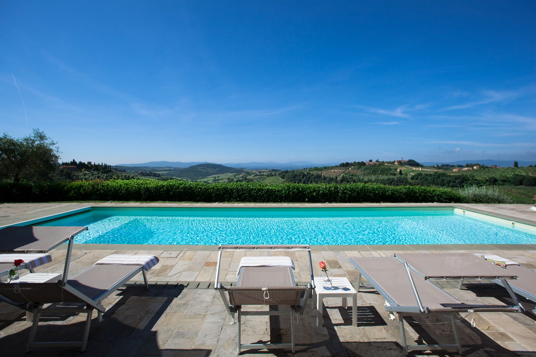 Pool area with sunbeds overlooking the hills at Villa di Tignano in Tuscany