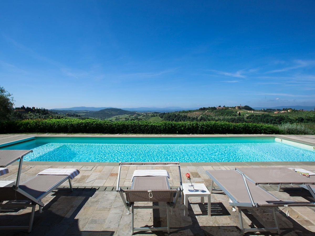Pool area with sunbeds overlooking the hills at Villa di Tignano in Tuscany