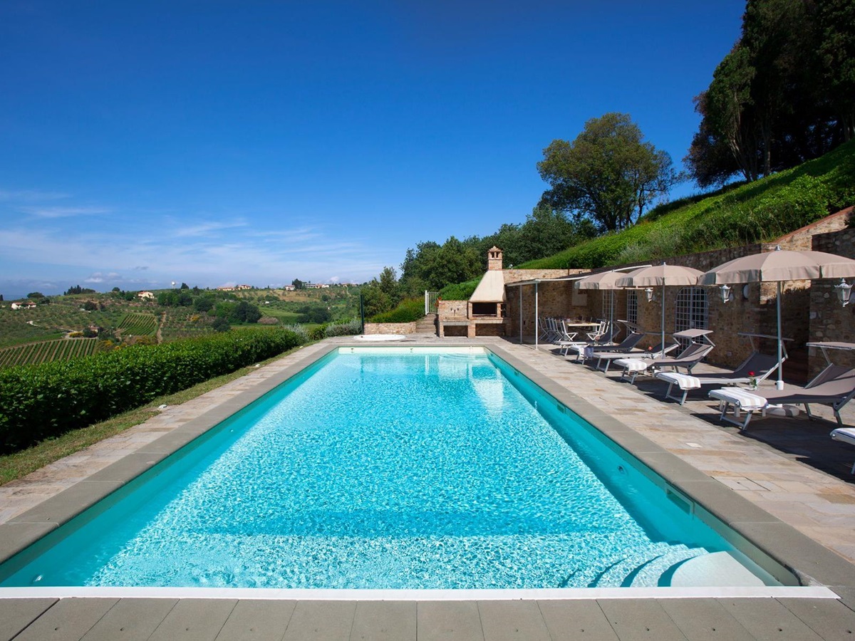 Pool area with sunbeds at the right and view of the hills on the left at Villa di Tignano in Tuscany