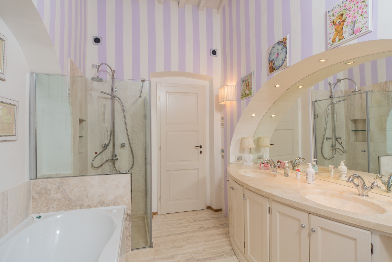 Bathroom with candy stripe walls, bath, shower, double sink and large mirror at Villa di Tignano in Tuscany, Italy