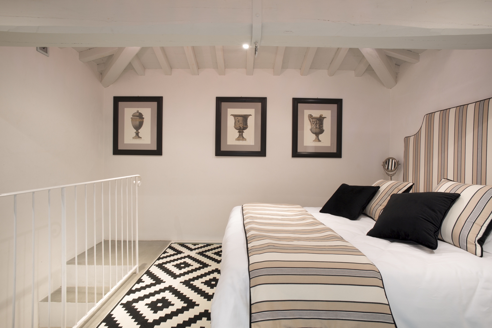 Bedroom with double bed, picture frames and stairs at Villa di Tignano in Tuscany, Italy