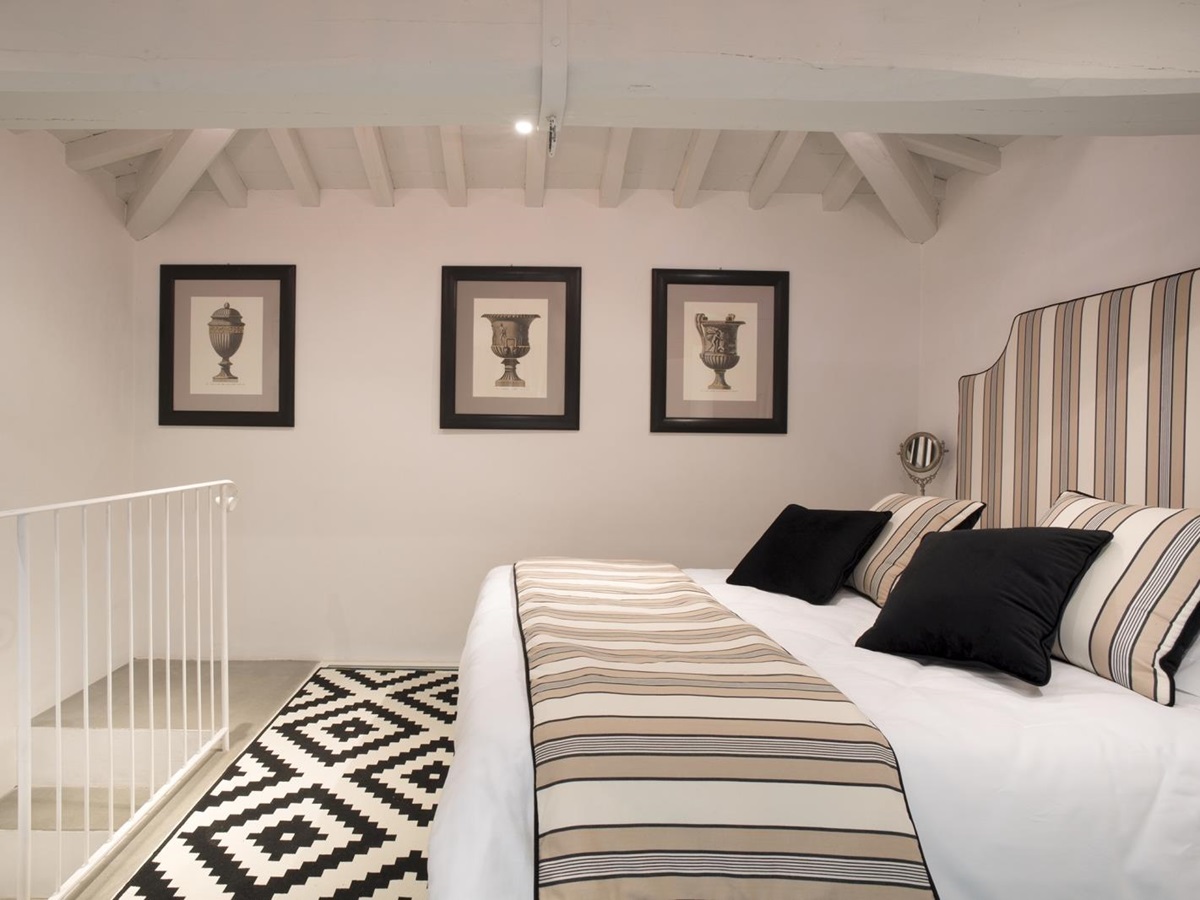 Bedroom with double bed, picture frames and stairs at Villa di Tignano in Tuscany, Italy