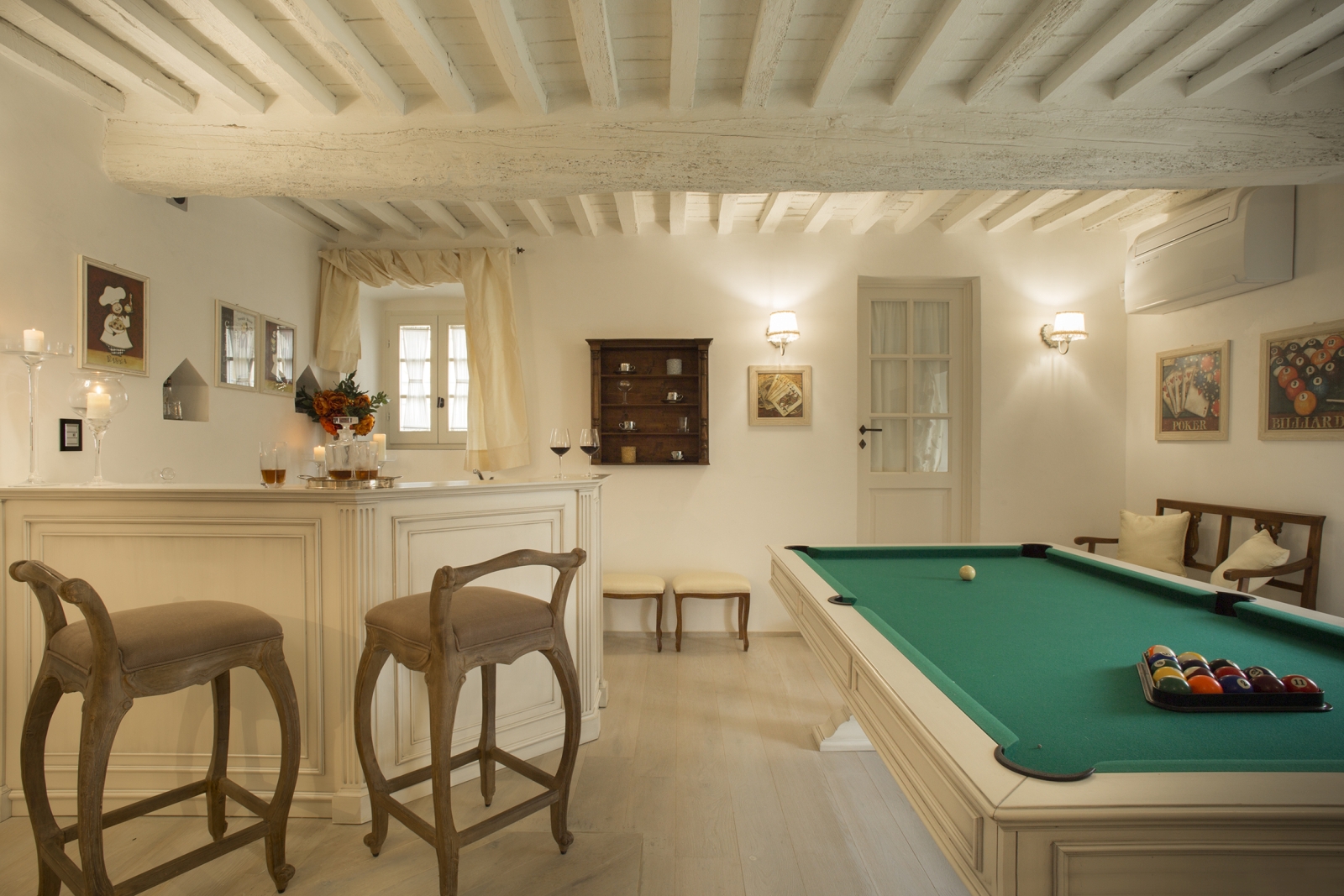 Games room with pool table, bar, bar stools, picture frames and lights at Villa di Tignano in Tuscany, Italy