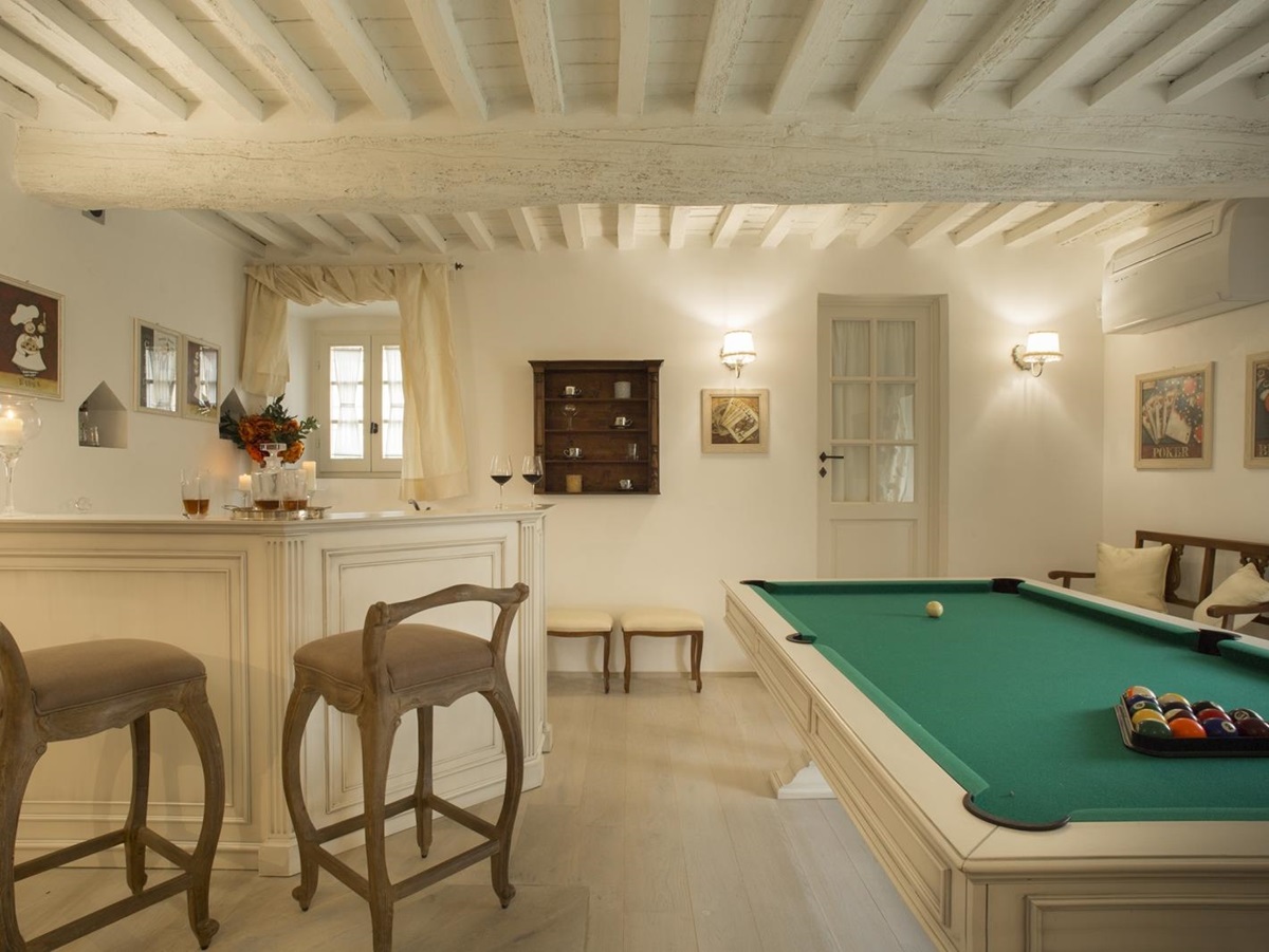 Games room with pool table, bar, bar stools, picture frames and lights at Villa di Tignano in Tuscany, Italy