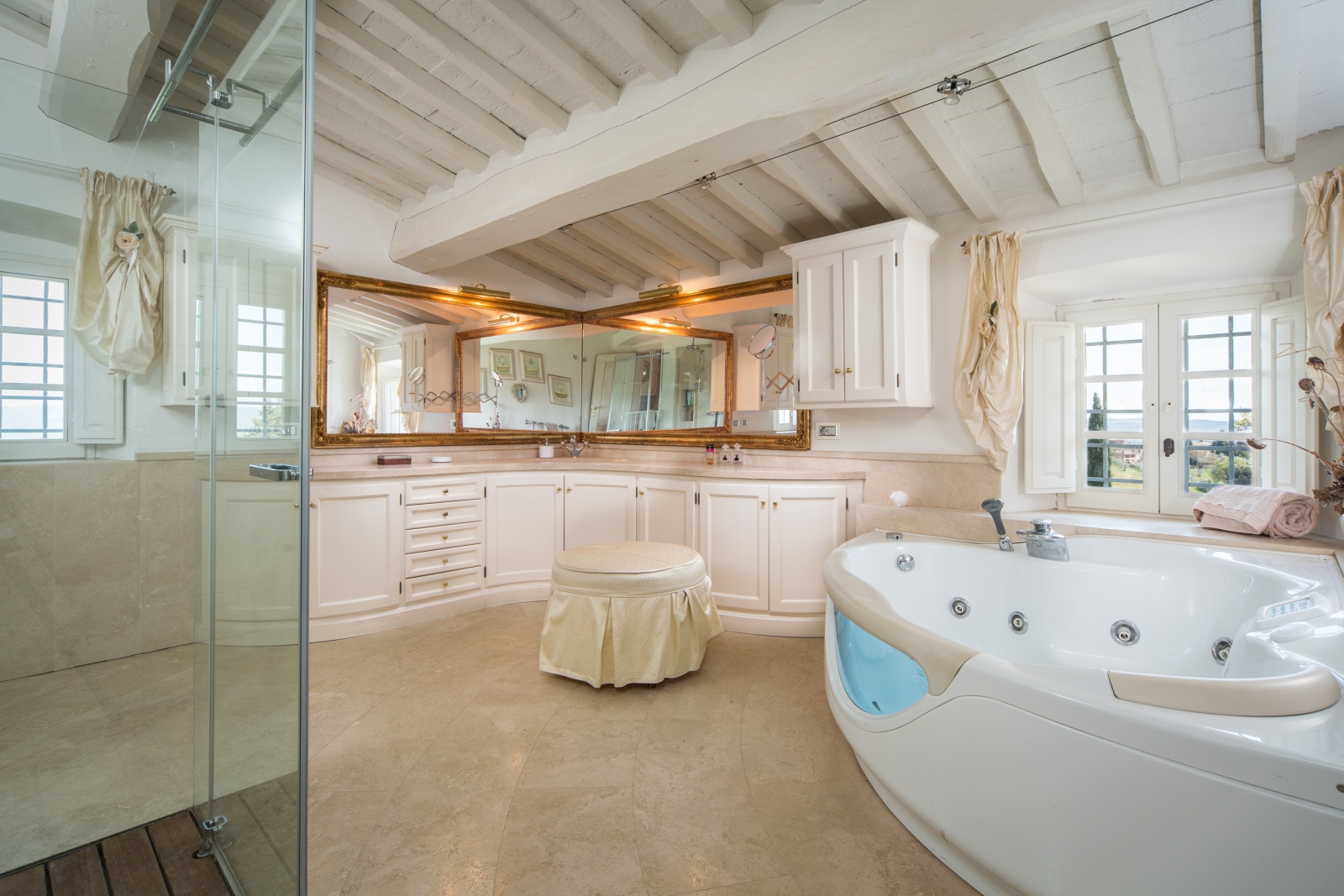 Large master bathroom with jacuzzi bath, shower and large sink unit with mirrors at Villa di Tignano in Tuscany, Italy
