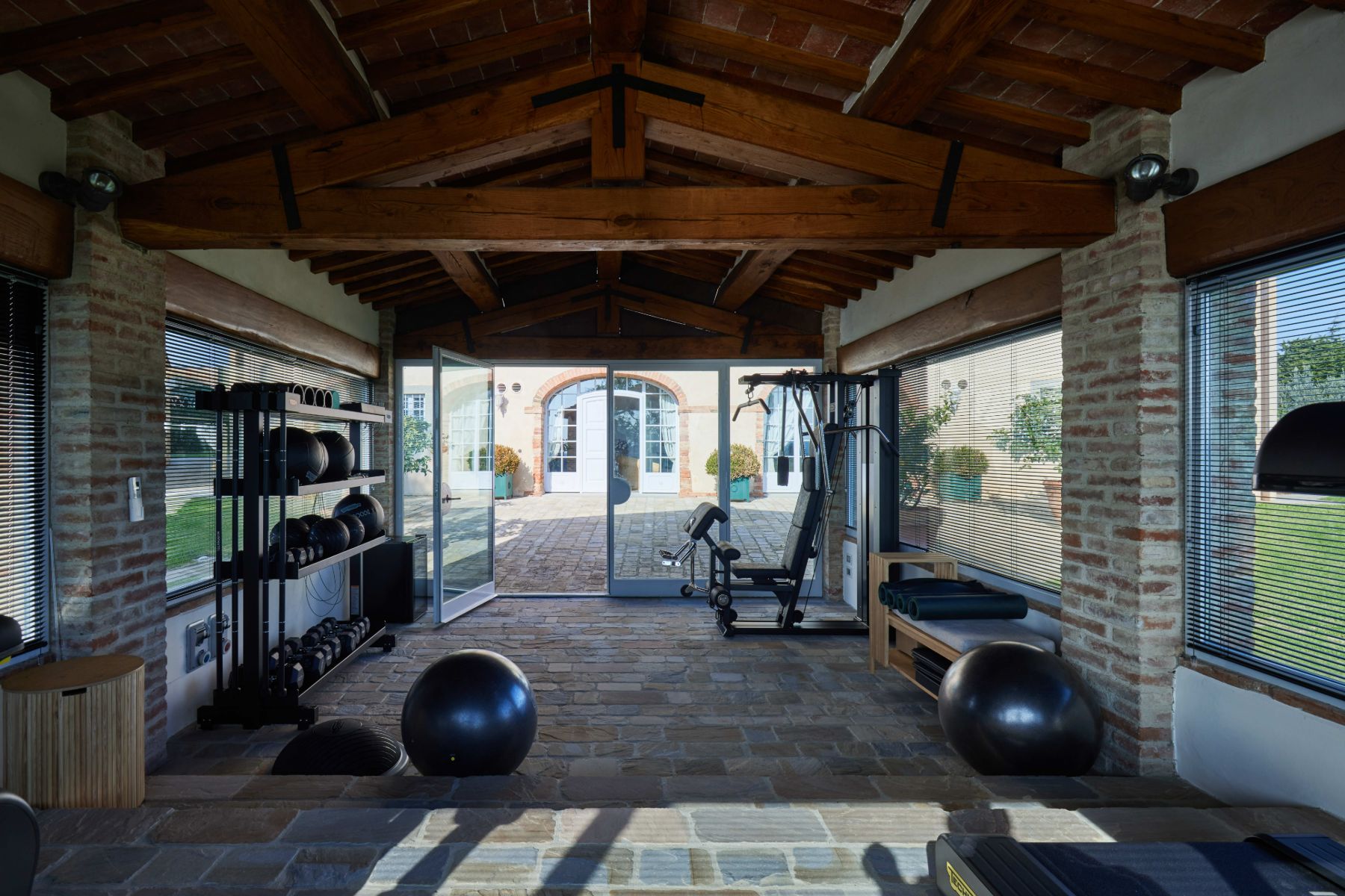 Gym in the palestro building with gym equipment and stone floors at Villa di Tignano in Tuscany