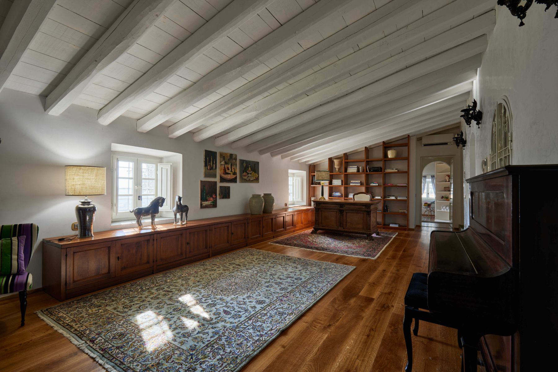 Long room with a piano and wooden desk at Villa di Tignano in Tuscany