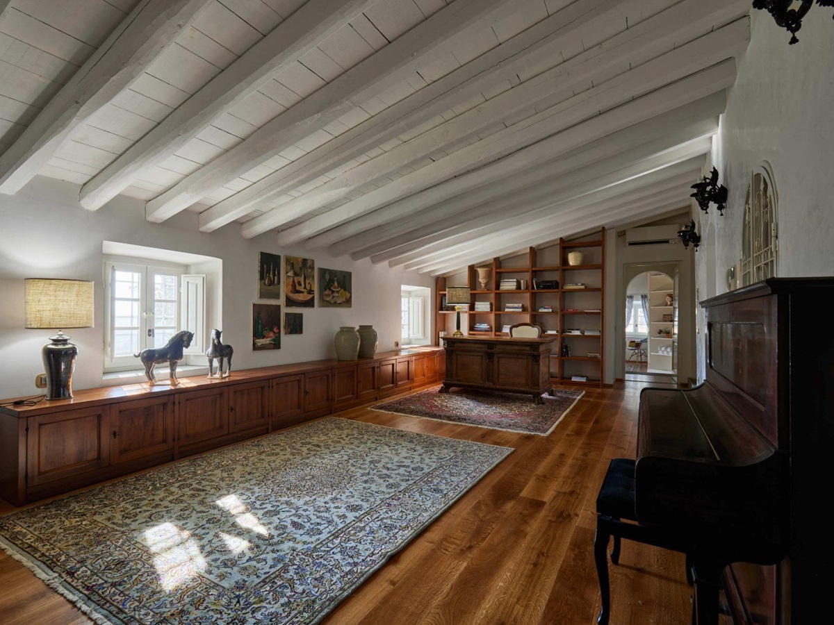 Long room with a piano and wooden desk at Villa di Tignano in Tuscany