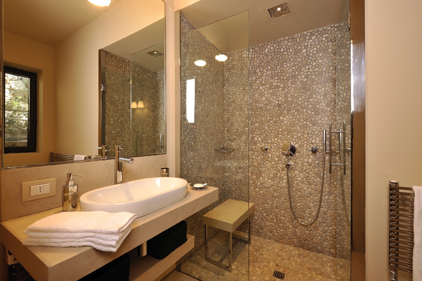 A tiled bathroom with walk-in shower and large basin